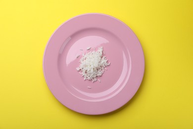 Photo of Plate with cooked rice on yellow background, top view