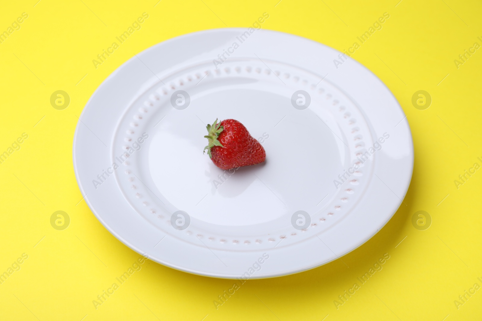 Plate with fresh strawberry on yellow background, closeup Photo of Plate with fresh strawberry on yellow background, closeup