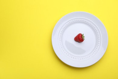 Photo of Plate with fresh strawberry on yellow background, top view. Space for text