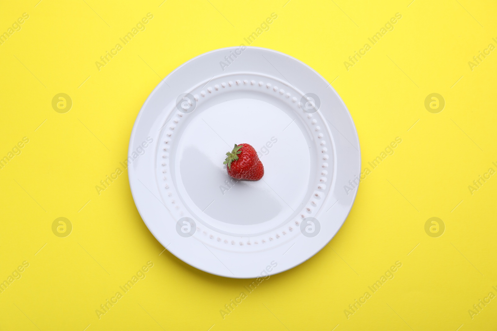 Plate with fresh strawberry on yellow background, top view Photo of Plate with fresh strawberry on yellow background, top view