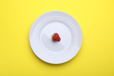 Photo of Plate with fresh strawberry on yellow background, top view