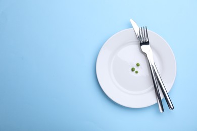 Photo of Plate with fresh green peas and cutlery on light blue background, top view. Space for text