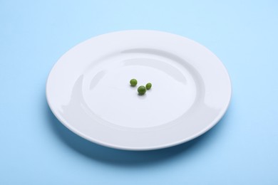 Photo of Plate with fresh green peas on light blue background, closeup