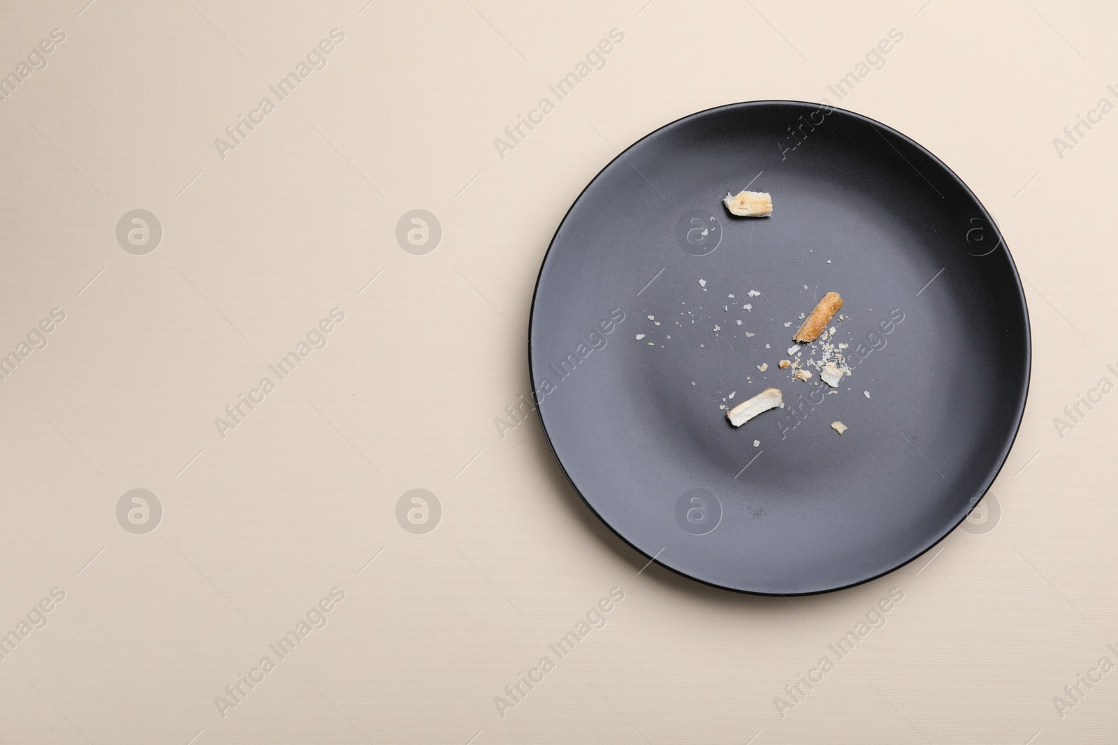 Dirty plate with bread crumbs on beige background, top view. Space for text Photo of Dirty plate with bread crumbs on beige background, top view. Space for text