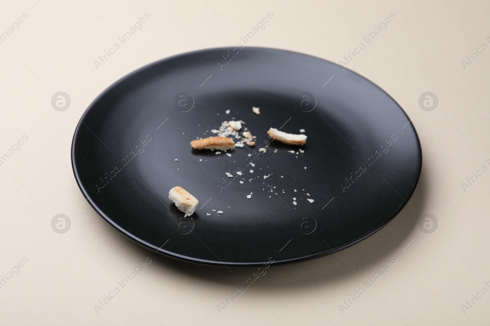 Dirty plate with bread crumbs on beige background, closeup Photo of Dirty plate with bread crumbs on beige background, closeup
