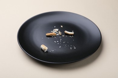 Photo of Dirty plate with bread crumbs on beige background, closeup