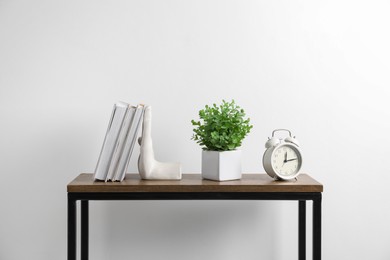 Photo of Different decor and alarm clock on wooden table near white wall indoors