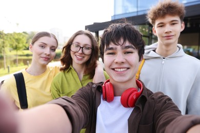 Photo of Group of happy teenagers taking selfie outdoors