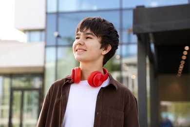 Photo of Portrait of happy teenager with headphones outdoors