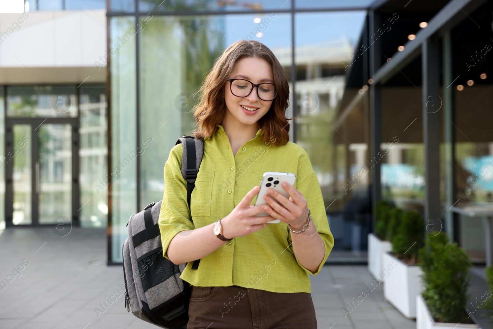 Teenage girl with smartphone and backpack outdoors Photo of Teenage girl with smartphone and backpack outdoors