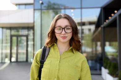 Photo of Teenage girl with backpack near building outdoors