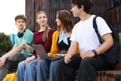 Photo of Teenagers with different devices on bench in park