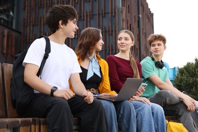 Photo of Teenagers with laptop on bench in park