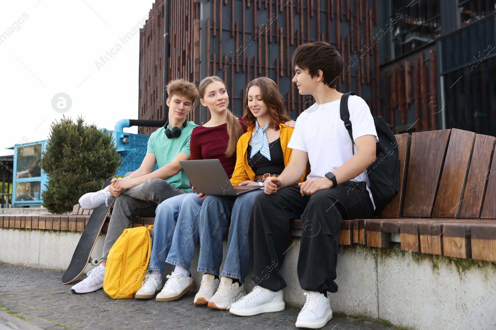 Teenagers with laptop on bench in park Photo of Teenagers with laptop on bench in park