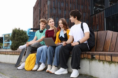 Photo of Teenagers with laptop on bench in park