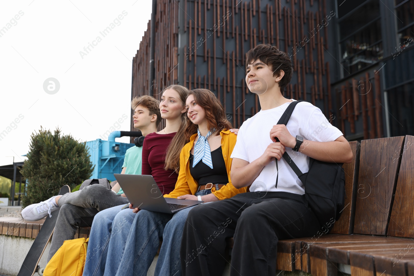 Teenagers with laptop on bench in park Photo of Teenagers with laptop on bench in park