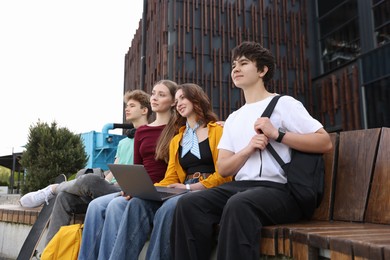 Photo of Teenagers with laptop on bench in park