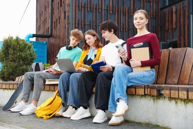 Photo of Group of teenagers studying together on bench outdoors