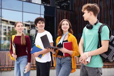 Photo of Teenagers with laptop and books near building outdoors