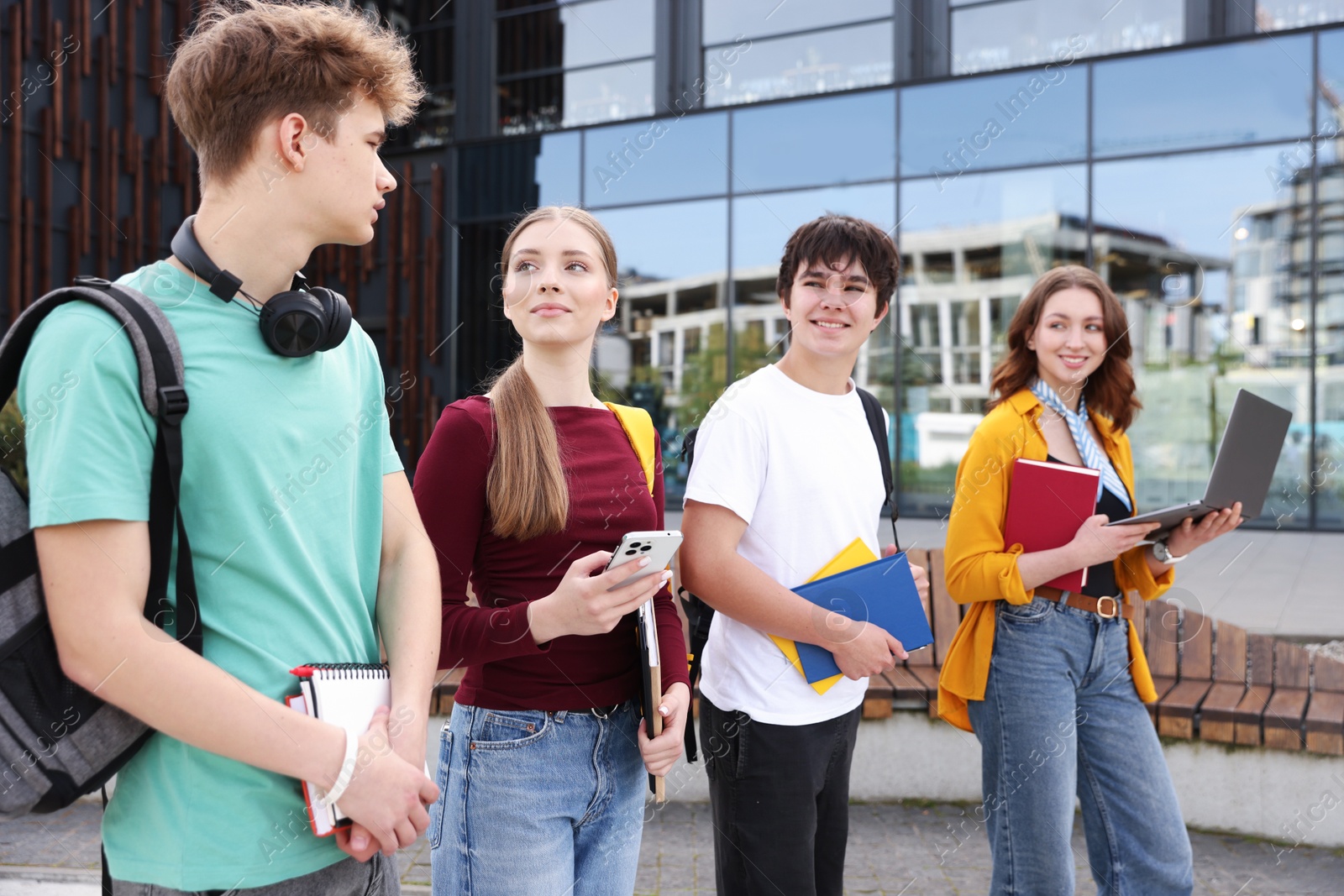 Teenagers with laptop and books near building outdoors Photo of Teenagers with laptop and books near building outdoors