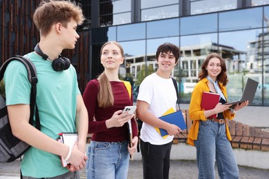 Photo of Teenagers with laptop and books near building outdoors