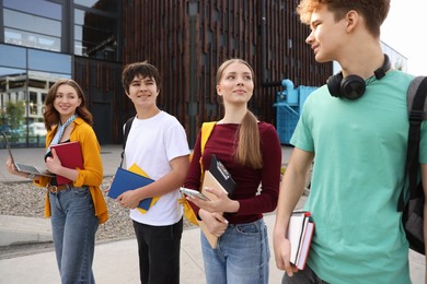 Photo of Teenagers with laptop and books near building outdoors