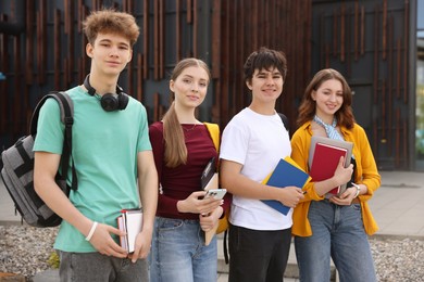 Photo of Group of teenagers with books near building outdoors