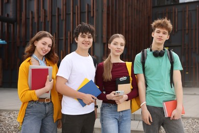 Photo of Group of teenagers with books near building outdoors
