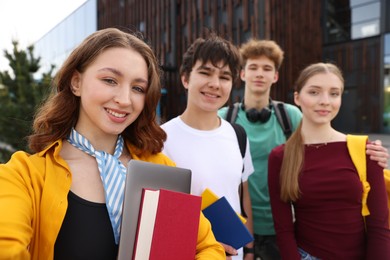 Photo of Group of happy teenagers taking selfie outdoors, selective focus