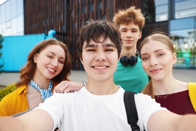 Photo of Group of happy teenagers taking selfie outdoors, selective focus