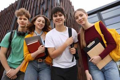 Photo of Group of happy teenagers near building outdoors, low angle view