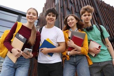 Photo of Group of happy teenagers near building outdoors, low angle view
