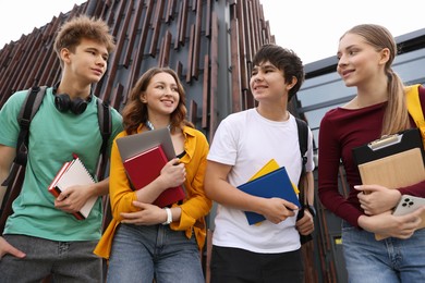Photo of Group of happy teenagers near building outdoors, low angle view