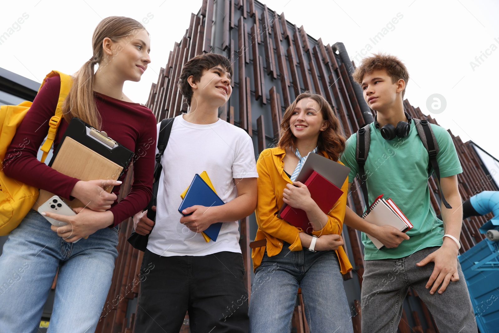 Group of happy teenagers near building outdoors, low angle view Photo of Group of happy teenagers near building outdoors, low angle view