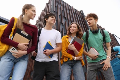 Photo of Group of happy teenagers near building outdoors, low angle view