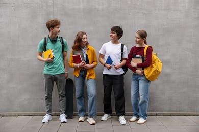 Photo of Group of teenagers near grey wall outdoors