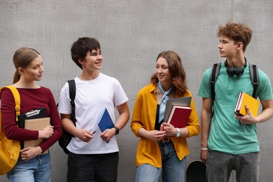 Photo of Group of teenagers near grey wall outdoors