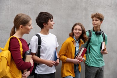 Photo of Group of teenagers near grey wall outdoors