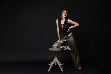 Photo of Beautiful woman in stylish outfit posing on black background, space for text