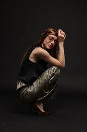 Photo of Full-length portrait of beautiful woman in stylish outfit on black background