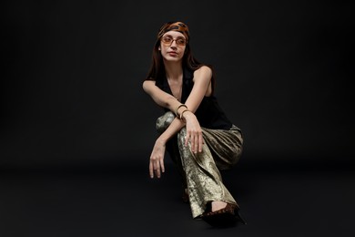 Photo of Full-length portrait of beautiful woman in stylish outfit on black background