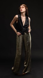 Photo of Full-length portrait of beautiful woman in stylish outfit on black background