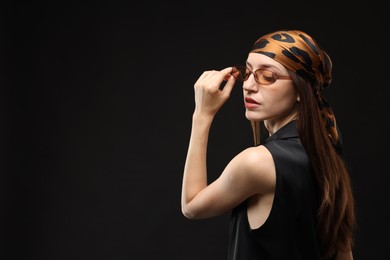 Photo of Portrait of beautiful woman in stylish outfit on black background, space for text