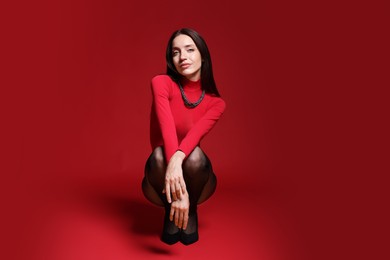 Photo of Full-length portrait of beautiful woman in stylish outfit on red background