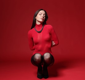 Photo of Full-length portrait of beautiful woman in stylish outfit on red background