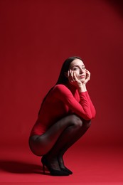 Photo of Full-length portrait of beautiful woman in stylish outfit on red background