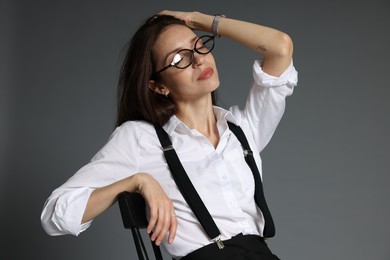 Photo of Beautiful woman in stylish outfit sitting on chair against grey background
