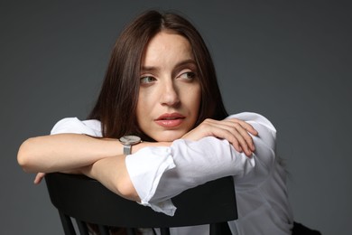 Photo of Beautiful woman in stylish outfit sitting on chair against grey background