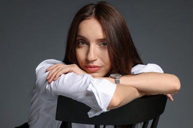 Photo of Beautiful woman in stylish outfit sitting on chair against grey background