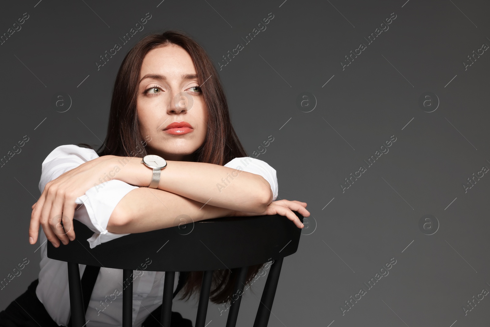 Beautiful woman in stylish outfit sitting on chair against grey background, space for text Photo of Beautiful woman in stylish outfit sitting on chair against grey background, space for text